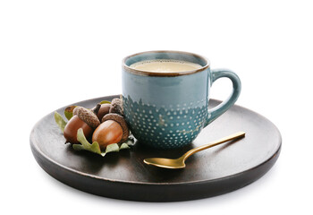 Plate with cup of coffee and acorns on white background