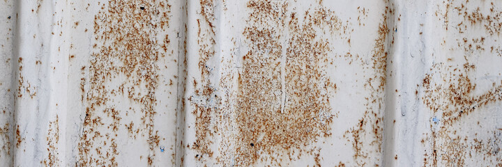 The texture of rusted metal painted in gray. Rough metal surface with rust. Rusty metal wall of a shipping container. Wide panoramic background for design.