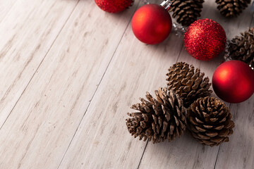 Pine cones and red christmas balls for christmas decoration on rustic white wooden background. Copy space for your text