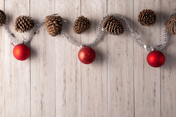 Pine cones and red christmas balls for christmas decoration on rustic white wooden background. Copy space for your text