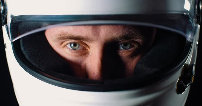 Man with strong blue eyes looking into the camera and closing the helmet visor in 4k slow motion close up of face