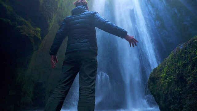 Male Hiker Watching The Gljufrabui Cascade Near The Seljalandsfoss In South Of Iceland. wide shot, rear
