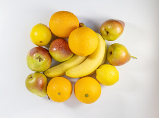 Top view of fresh fruit on a white background. Bananas, orange, lemon and pears on a white surface. The concept of proper and healthy nutrition