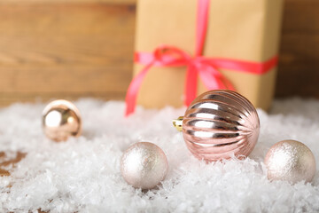 Christmas balls and heap of snow on wooden background, closeup