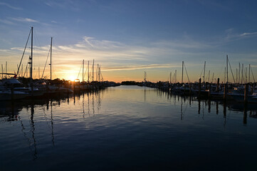 Boats docked in marina in Miami, Florida at sunrise on clear autumn morning.
