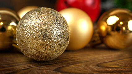 Golden christmas balls on a wooden background with lights and copy space