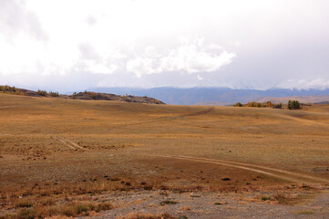 Obraz premium A field road going along the slope of a high hill in the desert steppe in autumn.