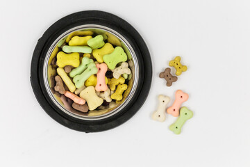 Gray bowl with snacks for dog on white background. Dog food and multicolored bones.
