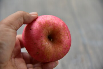 Fuji apples are moderately sized fruits, and have a round to ovate shape with a slightly lopsided appearance. The semi thick skin is smooth, waxy, and has a yellow green base, covered in red pink.
