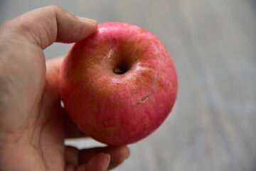 Fuji apples are moderately sized fruits, and have a round to ovate shape with a slightly lopsided appearance. The semi thick skin is smooth, waxy, and has a yellow green base, covered in red pink.