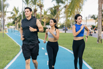 Obraz premium Group of three hispanic young adults running at a public path. Front view