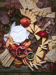 Winter Charcuterie Board with Cheeses, Meat, Chocolate, and Pomegranate (overhead shot)