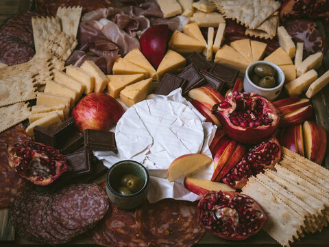 Winter Charcuterie Board with Cheeses, Meat, Chocolate, and Pomegranate (horizontal shot)