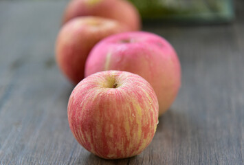 Fuji apples are moderately sized fruits, and have a round to ovate shape with a slightly lopsided appearance. The  skin is smooth, waxy, and has a yellow green base, covered in red pink stripes