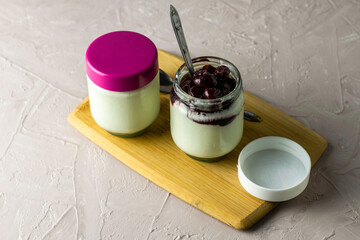 a jar of yogurt with cherry jam on a cutting board next to other jars of yogurt