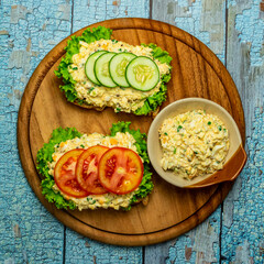 Homemade egg salad sandwich with wholewheat bun,cucumber, tomatoes,lettuce,egg,and cream cheese.  Rustic style. Selective Focus. Top view. Copy space. No.017