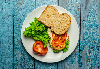Homemade egg salad sandwich with wholewheat bun,cucumber, tomatoes,lettuce,egg,and cream cheese.  Rustic style. Selective Focus. Top view. Copy space. No.10
