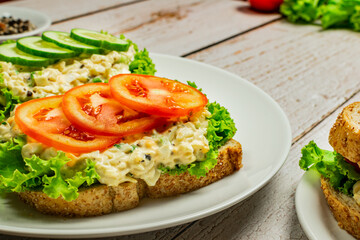 Homemade egg salad sandwich with wholewheat bun,cucumber, tomatoes,lettuce,egg,and cream cheese.  Rustic style. Selective Focus. Top view. Copy space. No.08