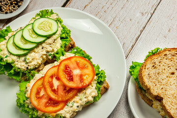 Homemade egg salad sandwich with wholewheat bun,cucumber, tomatoes,lettuce,egg,and cream cheese.  Rustic style. Selective Focus. Top view. Copy space. No.07