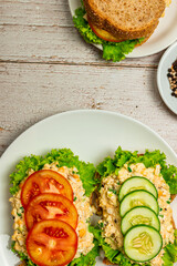 Homemade egg salad sandwich with wholewheat bun,cucumber, tomatoes,lettuce,egg,and cream cheese.  Rustic style. Selective Focus. Top view. Copy space. No.05