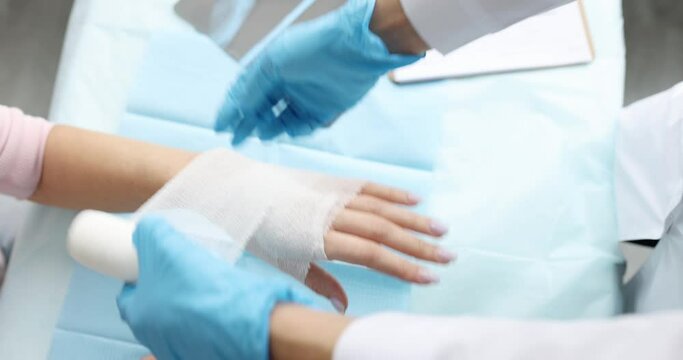 Doctor traumatologist bandaging patient hand with bandage in clinic closeup 4k movie