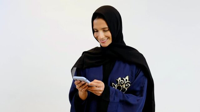 Woman using mobile smart phone on Abaya and Shayla Hijab. Happy Middle East national on traditional Arab clothing