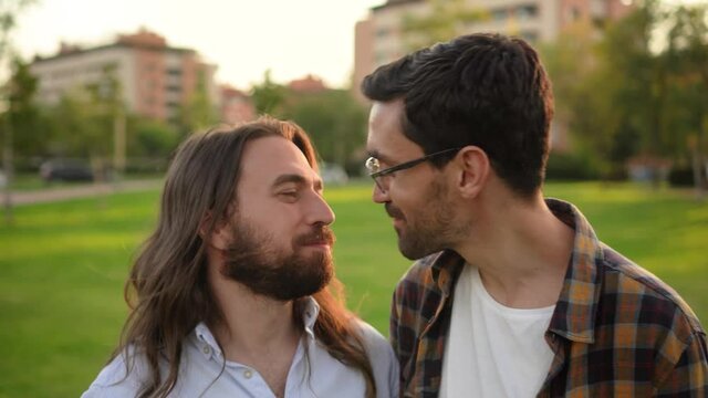 young gay male couple kissing in the park.