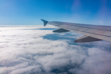 View from the airplane window at a beautiful cloudy sky and the airplane wing