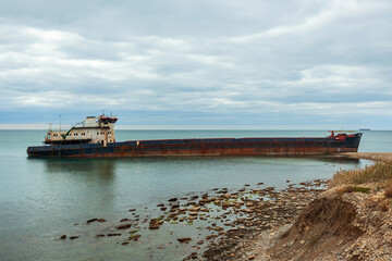 A long old ship wrecked on the Russian coast. The rusty drydocker was nosed against the shore and tilted.