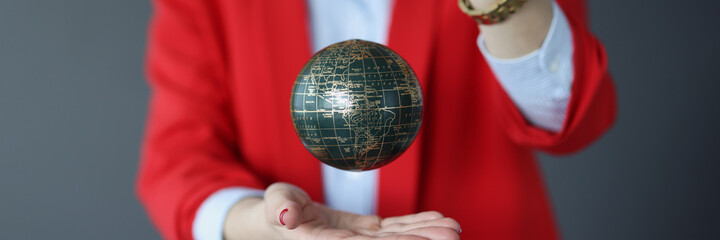 Woman in a business suit holds ball with world map - obrazy, fototapety, plakaty