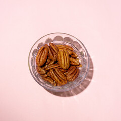 Walnuts in a glass bowl on pink background