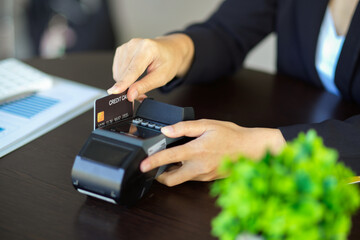 Close-up a female cashier swipe a credit card with a payment terminal