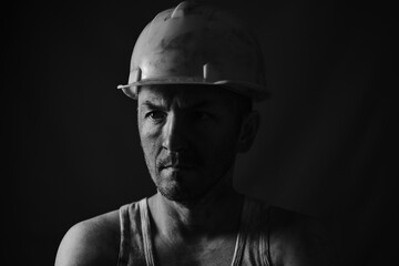 Portrait miner in helmet and undershirt with dirty face.