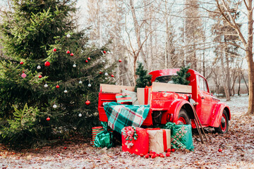 red car pickup truck decorated with Christmas wreath, blankets, pillows and gift boxes with presents is standing in forest, Santa Claus's magic transport, New Year and Christmas banner background - obrazy, fototapety, plakaty