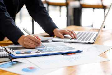 Close up a Business woman using calculator and laptop for doing math finance on a wooden desk, tax, accounting, statistics, and analytical research concept