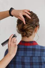 Fototapeta premium process hair styling in hairdressing salon. Professional haircutter makes beautiful wedding hairstyle hands of Hairstyle master with comb makes evening festive hairstyle for young woman on background 