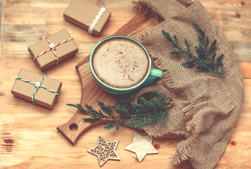Christmas atmosphere, a cup of coffee among natural materials, sprigs of a Christmas tree, canvas fabric on a wooden surface