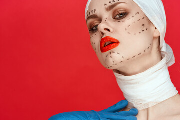 portrait of a woman in blue gloves syringe in hands contour on the face lifting red background
