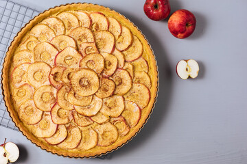Top view of Classic french apple tart on a grey background with apples and cinnamon sticks