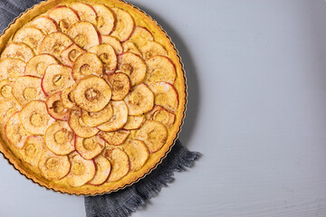 Top view of Classic french apple tart on a grey background with apples and cinnamon sticks