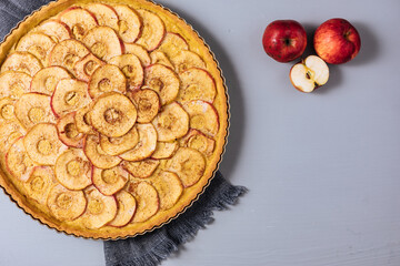 Top view of Classic french apple tart on a grey background with apples and cinnamon sticks