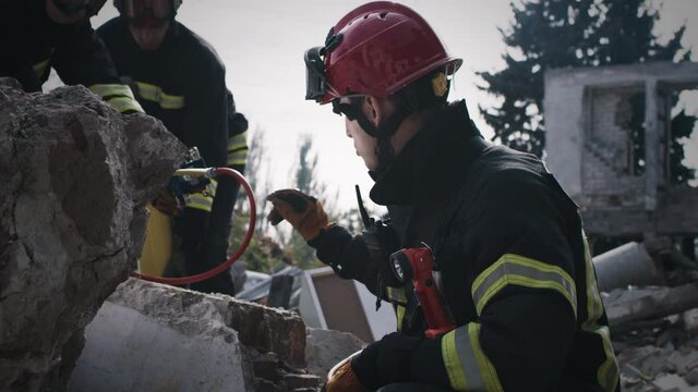 Man in protective hardhat and uniform talking with coworkers while searching for survivors during rescue mission after disaster