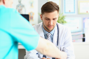 Obraz premium Male doctor sitting at the table, looking down, close-up