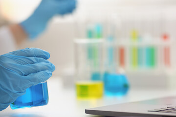 Microbiologist hands in gloves hold blue liquid