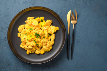 Breakfast with scrambled eggs on a dark background.