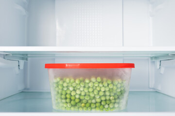 a container of fresh peas on a shelf in an empty refrigerator