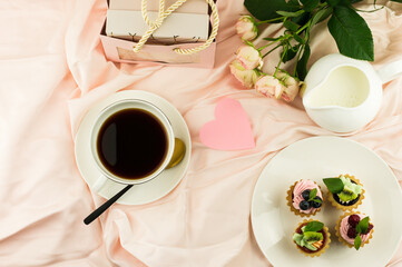 morning cup of coffee, mini tartilla, gift and bouquet of roses on Valentine's Day. romantic breakfast.