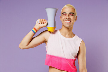 Young latin gay man with make up wearing bright pink top hold scream in megaphone announces...