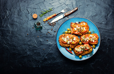 Meat schnitzel with cheese, olives and tomato