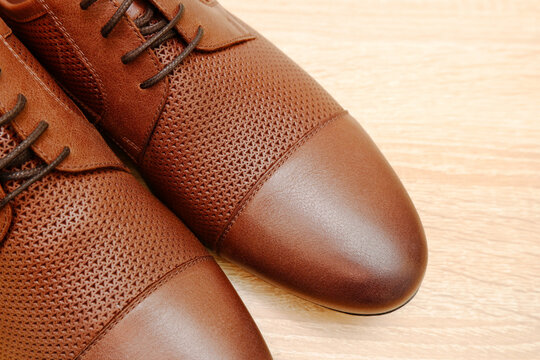 Leather men's light brown shoes standing on a wooden floor.Sale of men's classic shoes, business style shoes, shoe care, repair shop.Copyspace